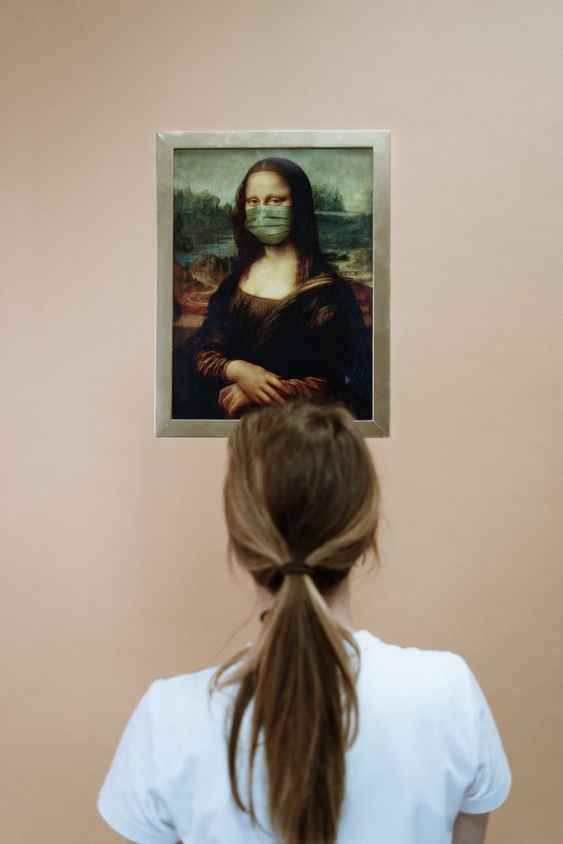 woman looking at a painting of mona lisa wearing face mask